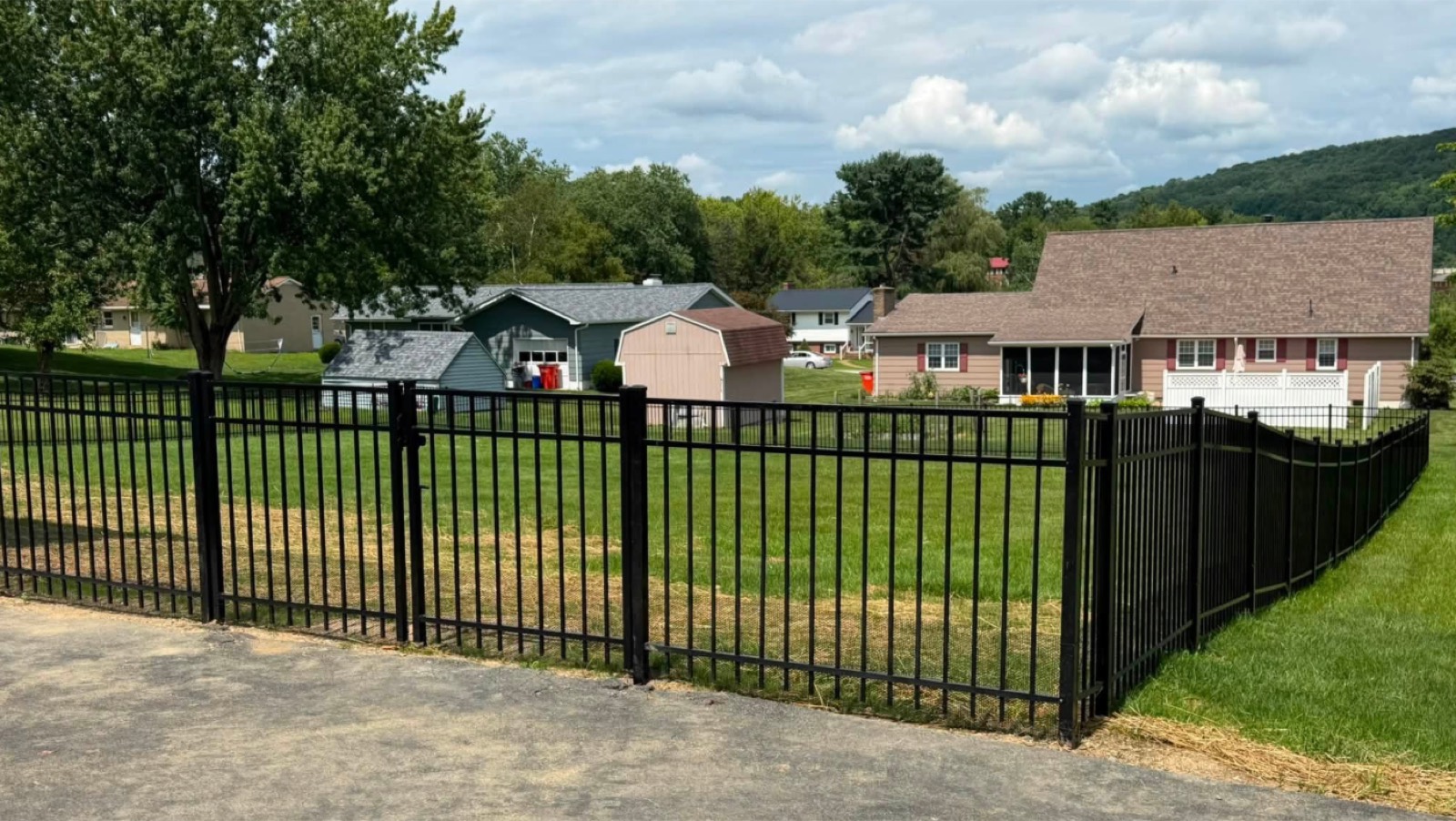 Black aluminum fence installation across a residential yard