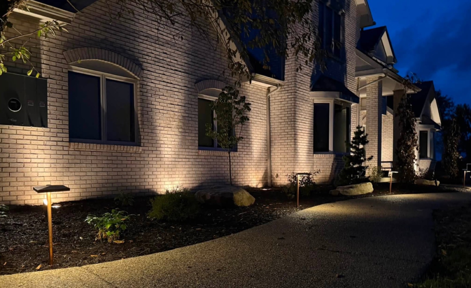 Landscape lighting uplighting the front of a home at dusk
