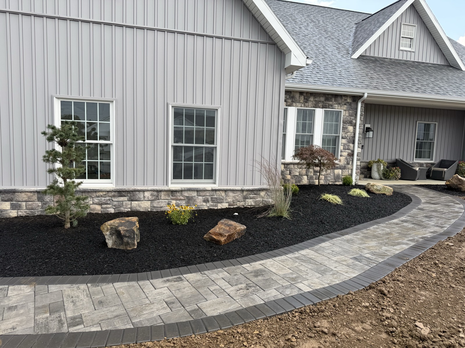 New-construction home with fresh foundation plantings, boulders and mulch beds