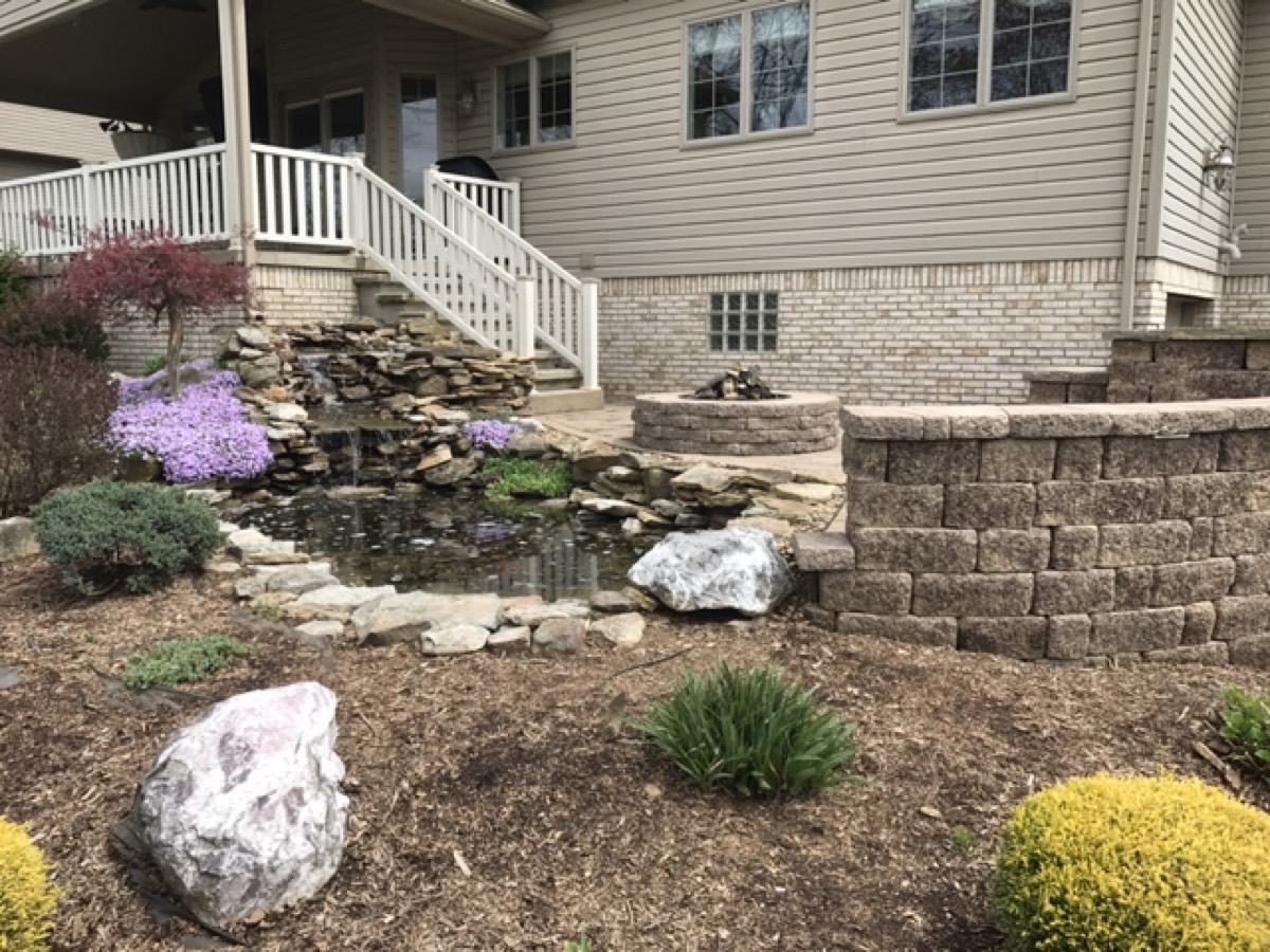 Landscaping with a paver patio and backyard pond