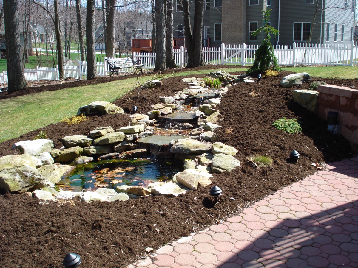 Backyard pond surrounded by mulch landscaping