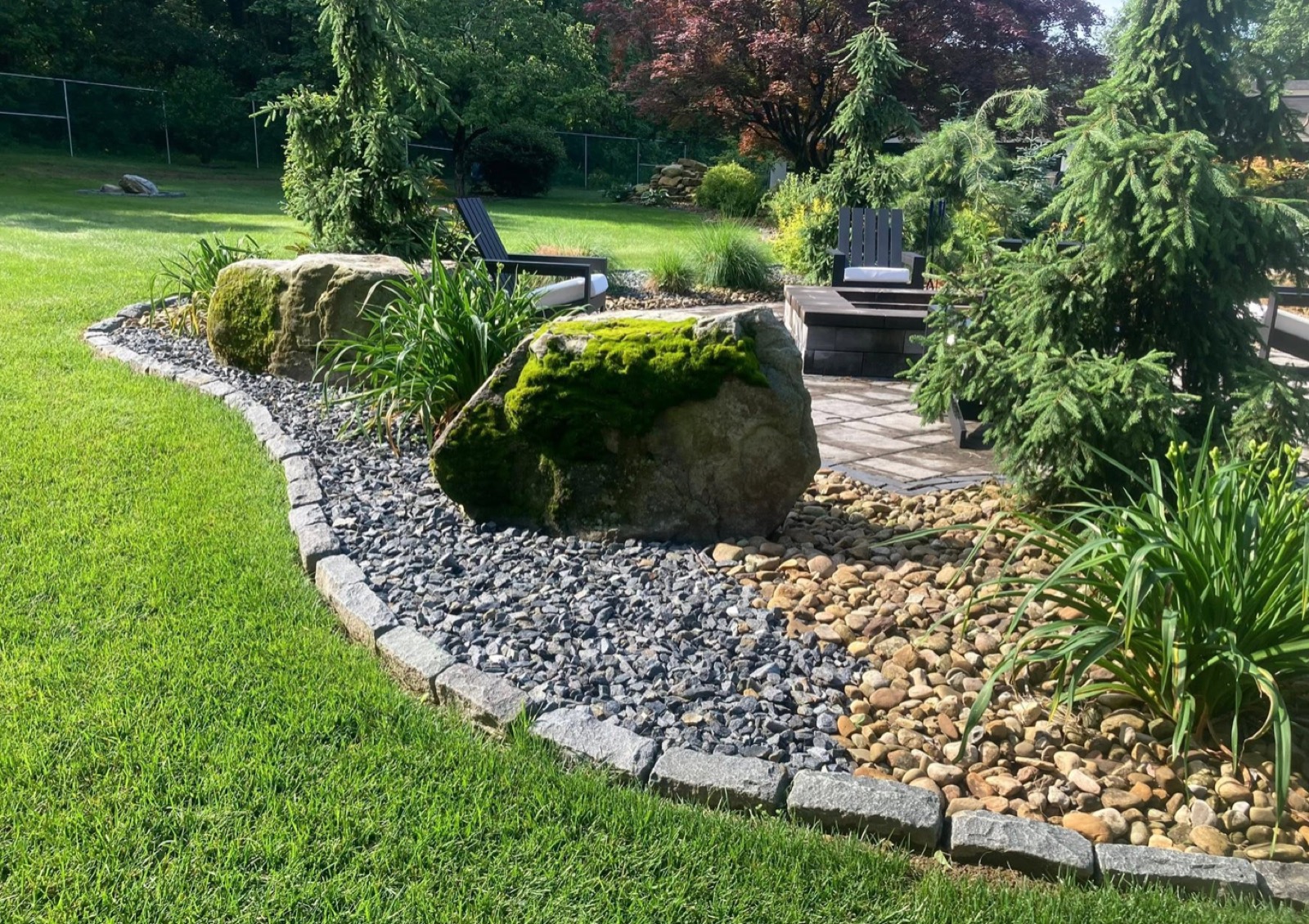 Landscape bed with river-rock drainage, boulders and cobblestone edging