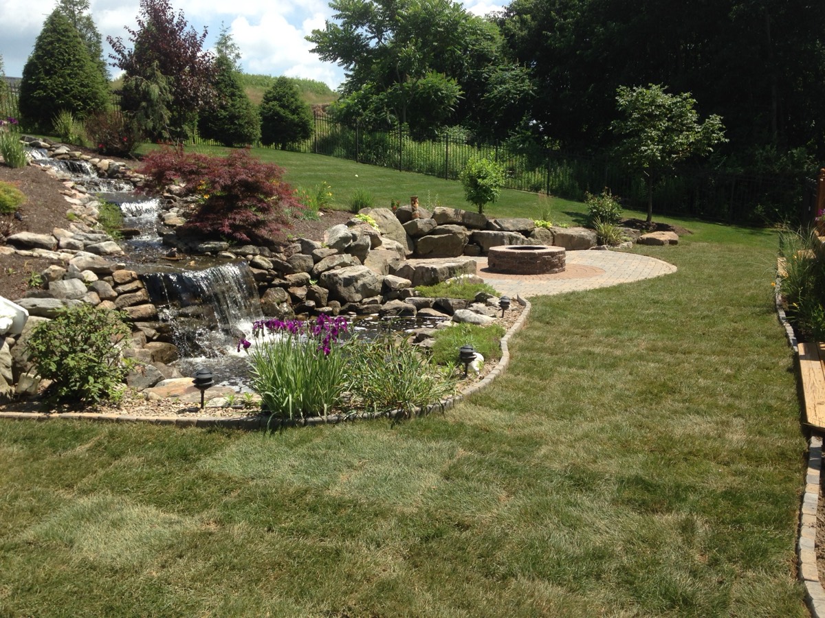 Natural hardscape with water feature and outdoor fireplace