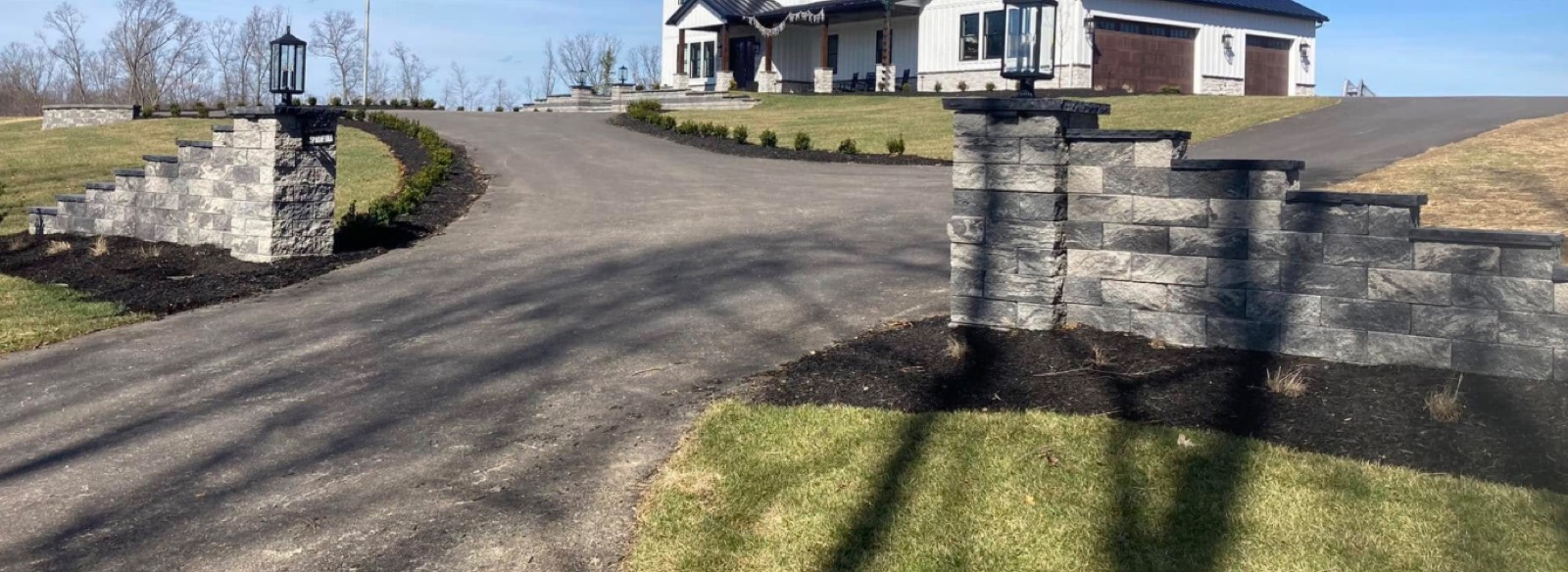 Stone entry columns with lighting at a driveway entrance