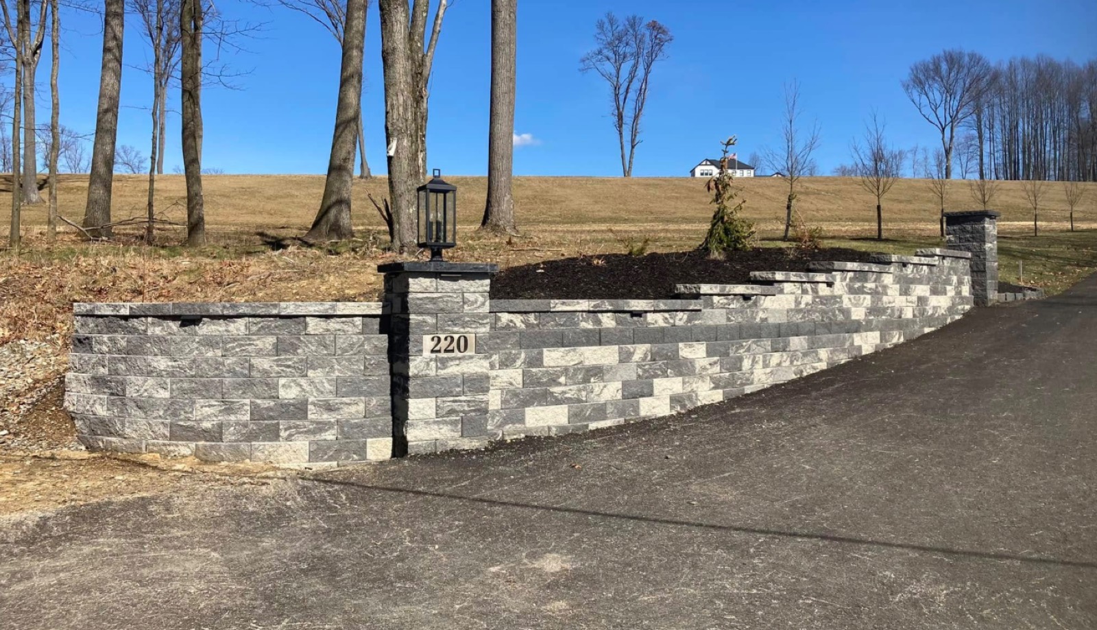Block entrance wall with address stone and lamp post at a driveway