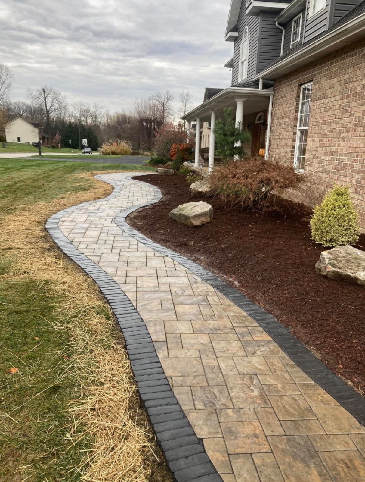 Curved paver walkway winding along a mulch bed