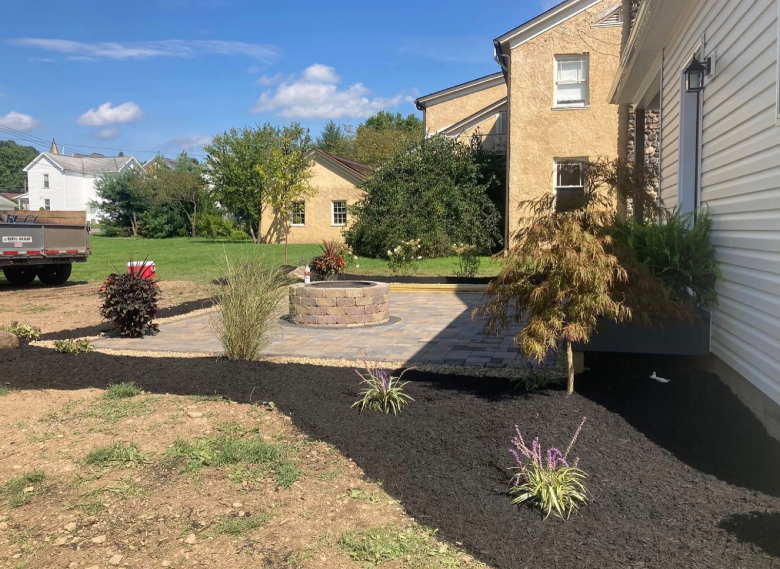 Paver patio with a fire feature and surrounding mulch beds