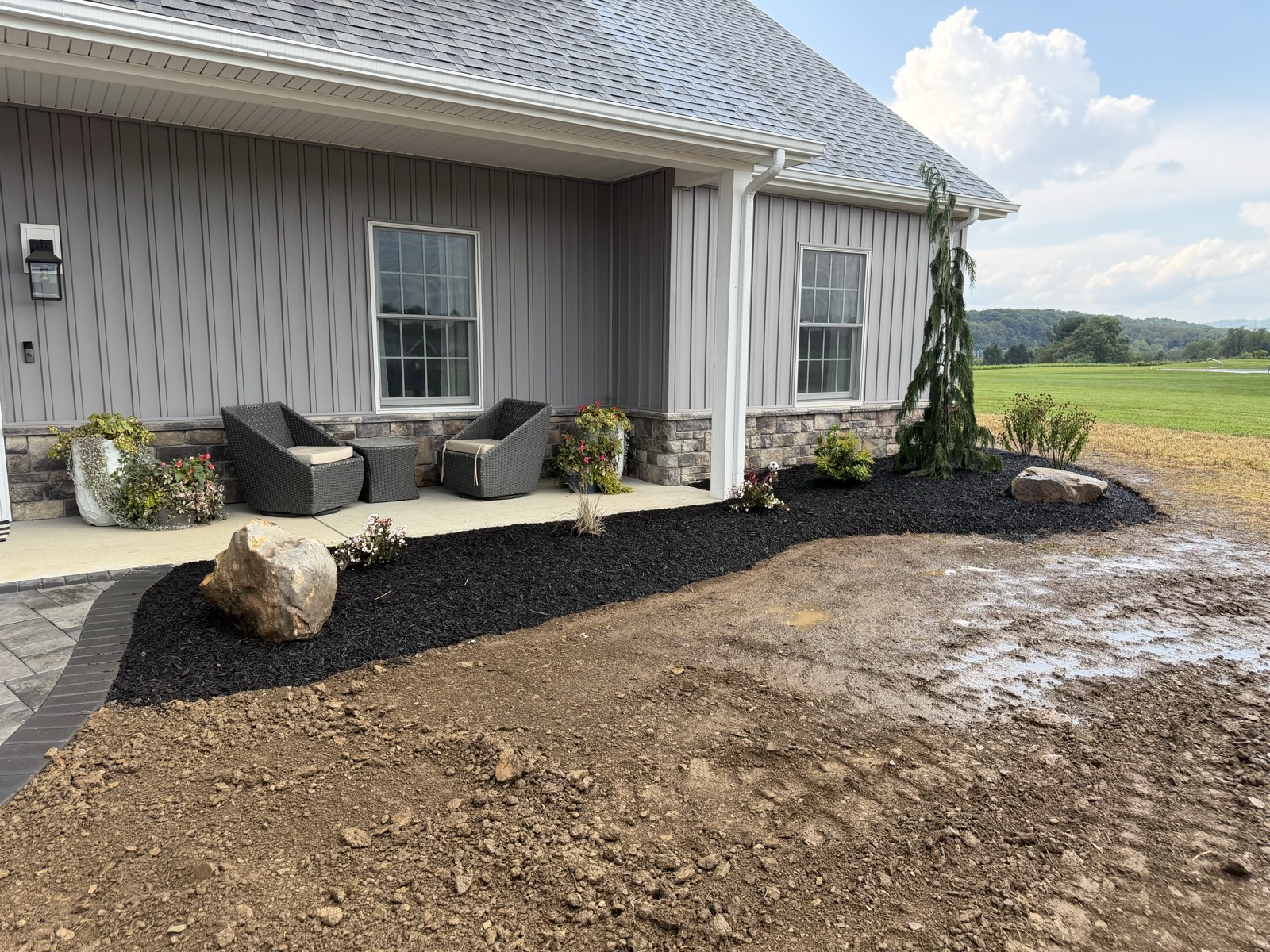 Paver patio with seating beside a new-construction home