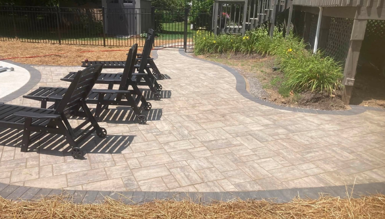 Paver patio with Adirondack seating beside a pool fence