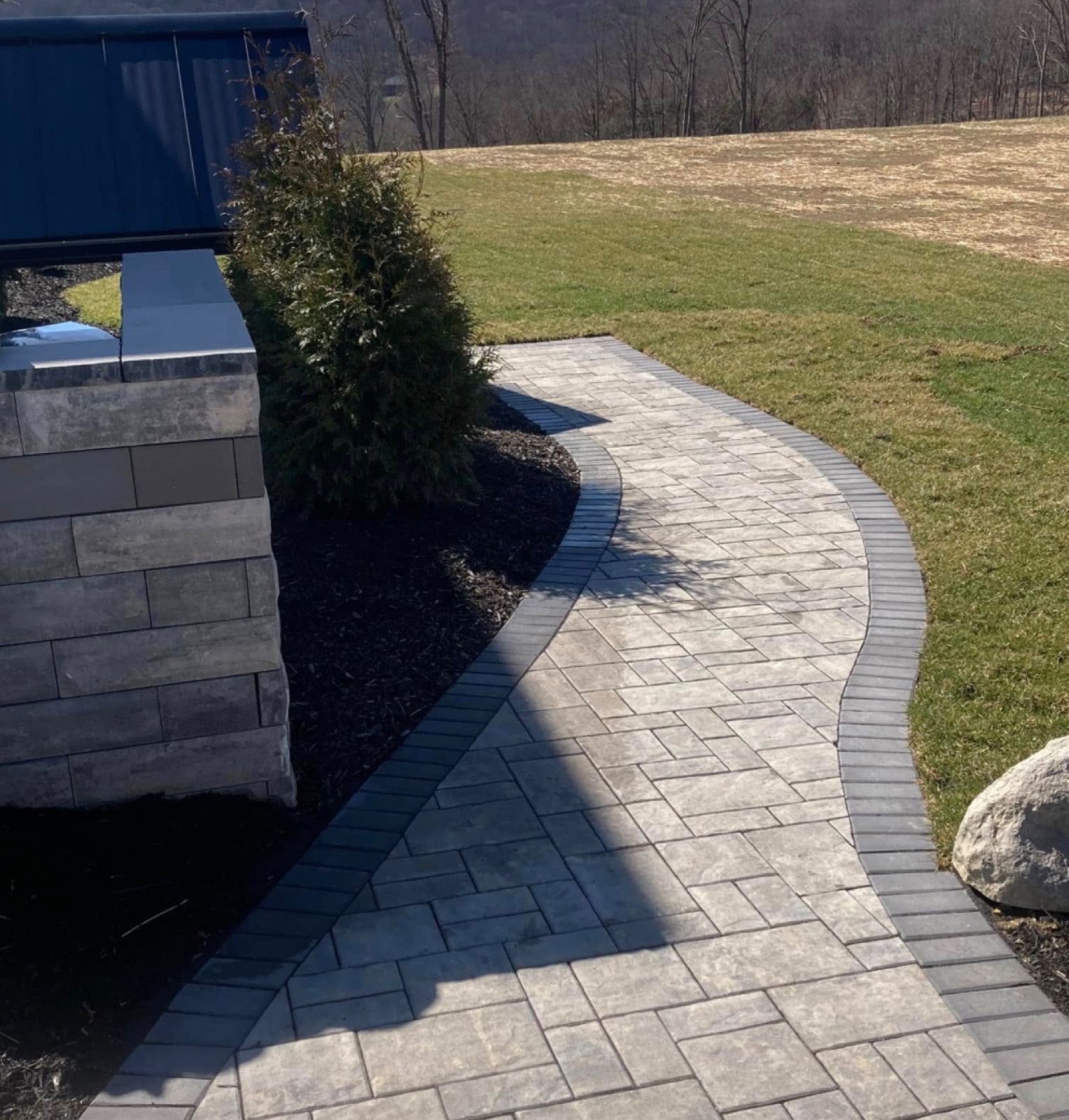 Paver walkway beside a stone column with a mountain view